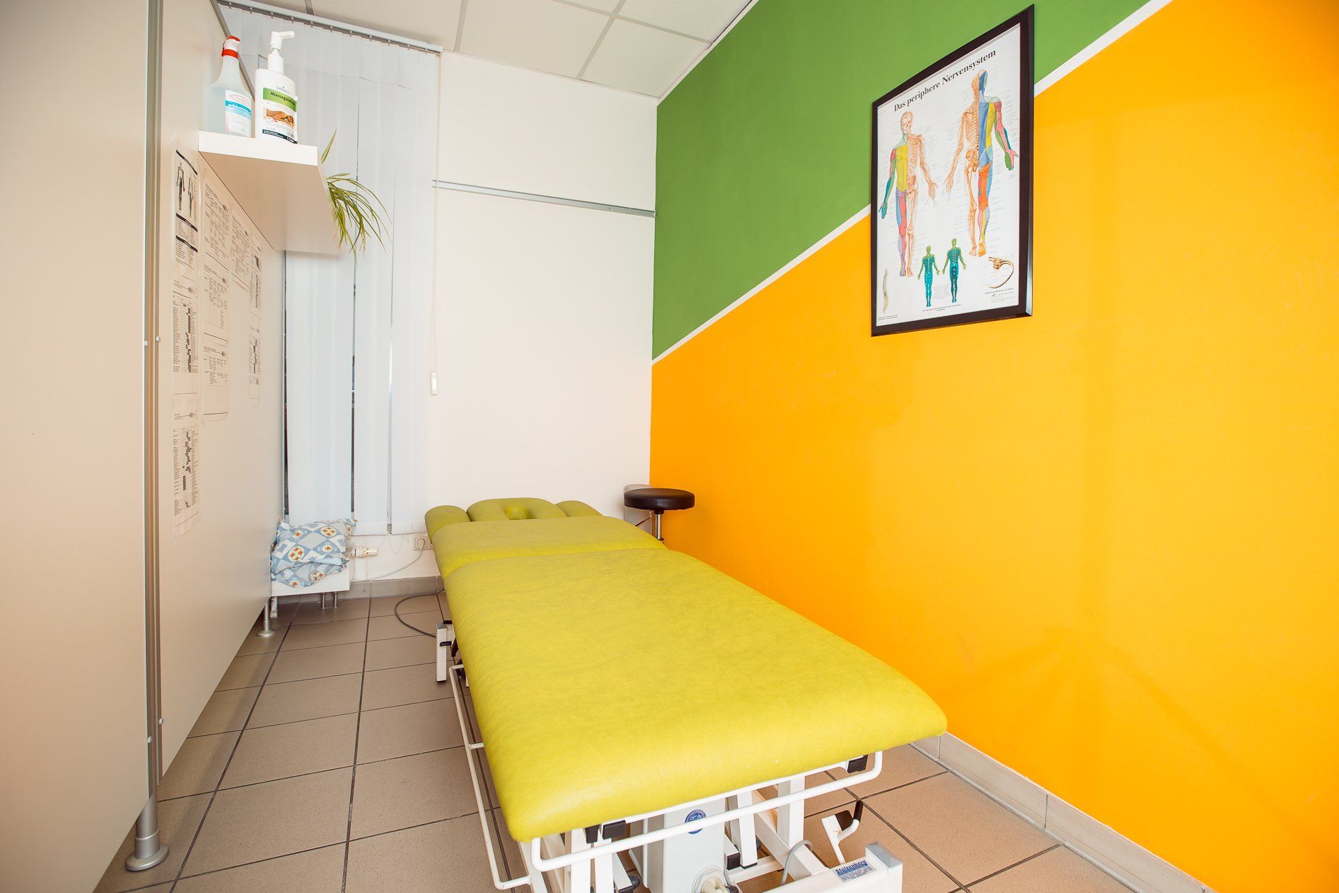 Behandlungsraum mit Therapieliege und anatomischer Tafel in Dresden Mickten